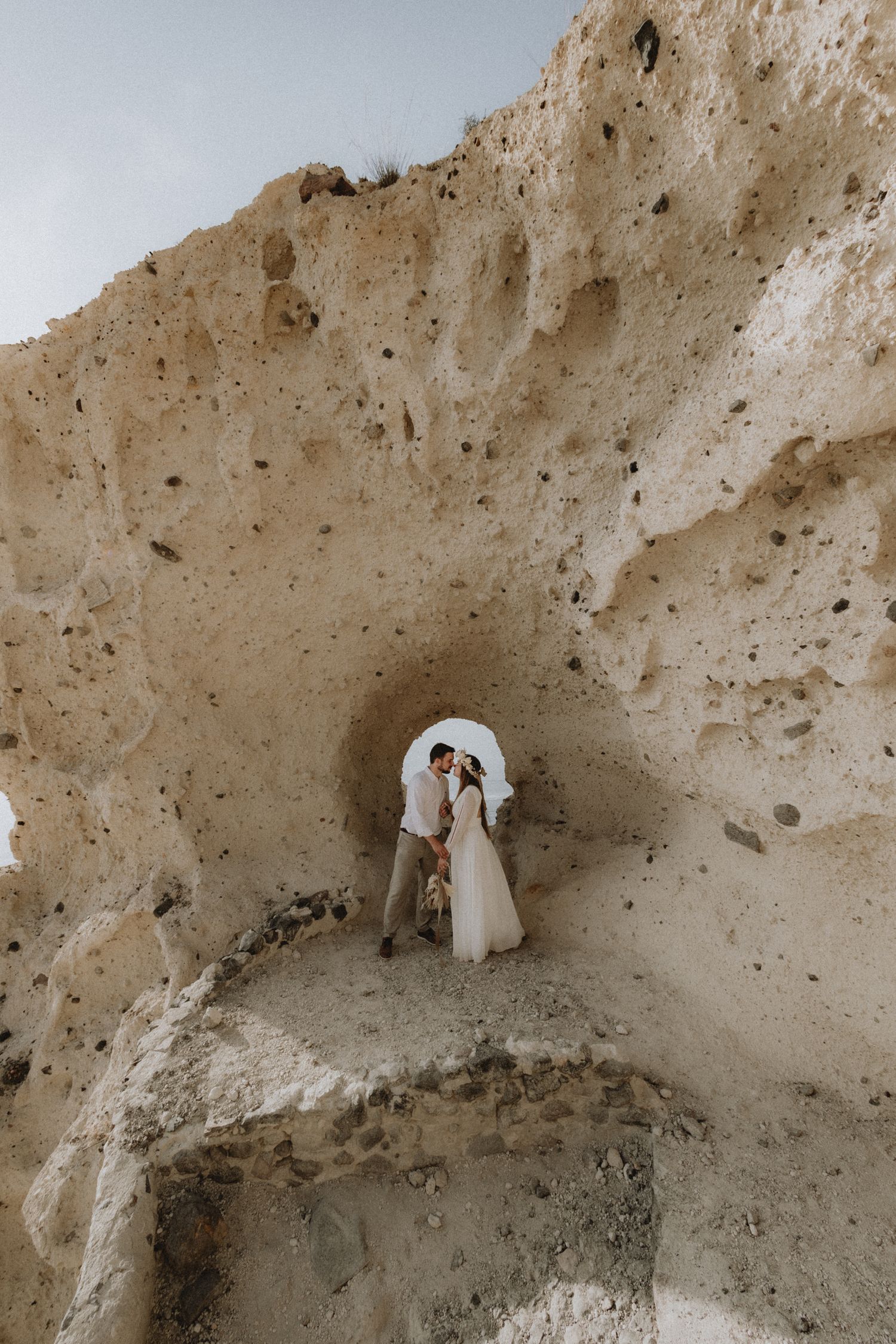 bride and groom kissing in front of a cliff in Santorini Greece