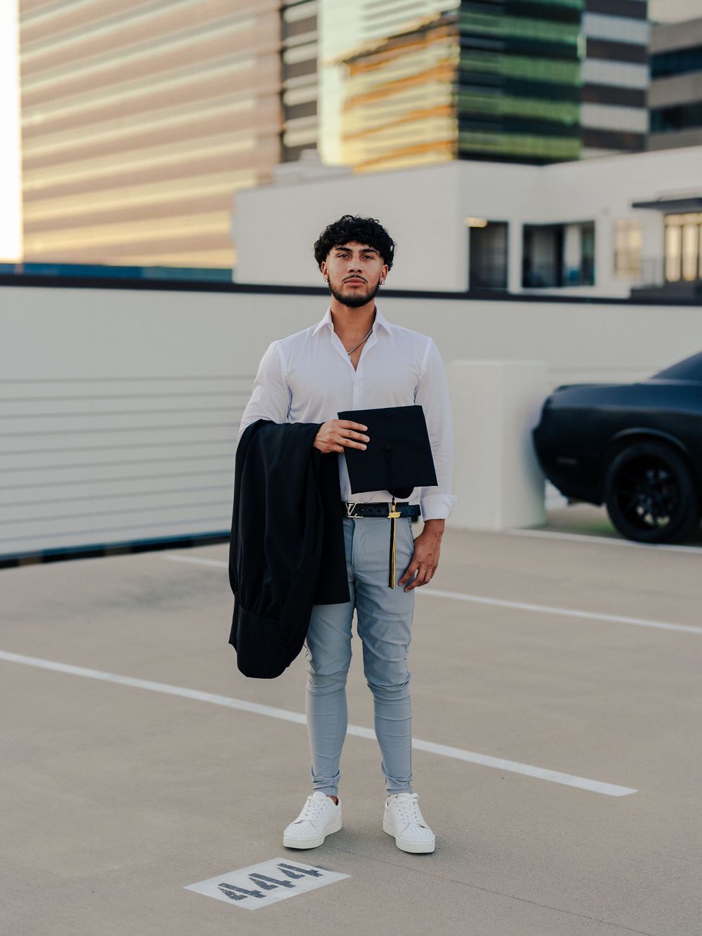 Business casual look with black jacket and portfolio in modern parking structure.