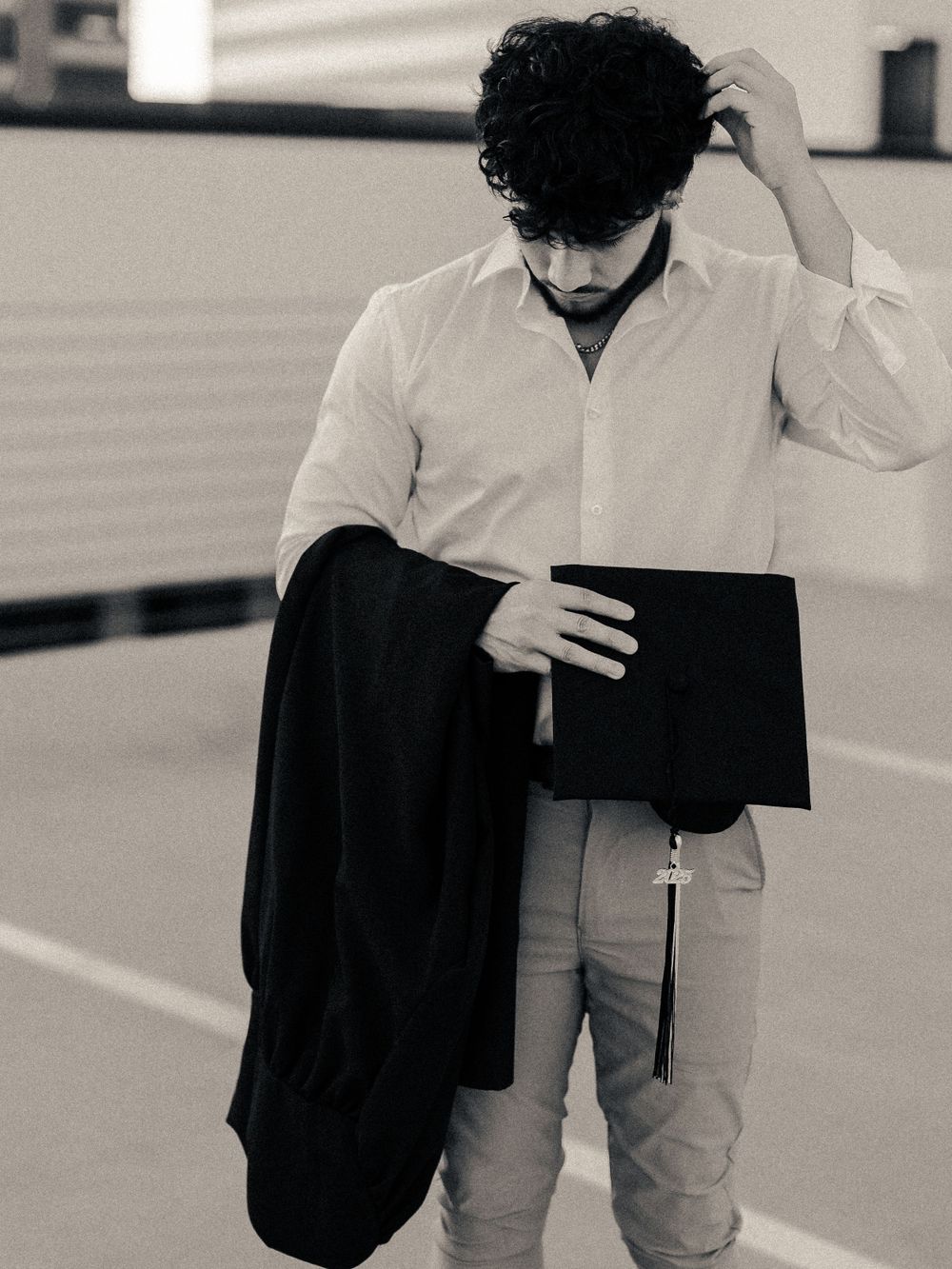 Black and white portrait showing business attire with jacket and portfolio in parking lot.