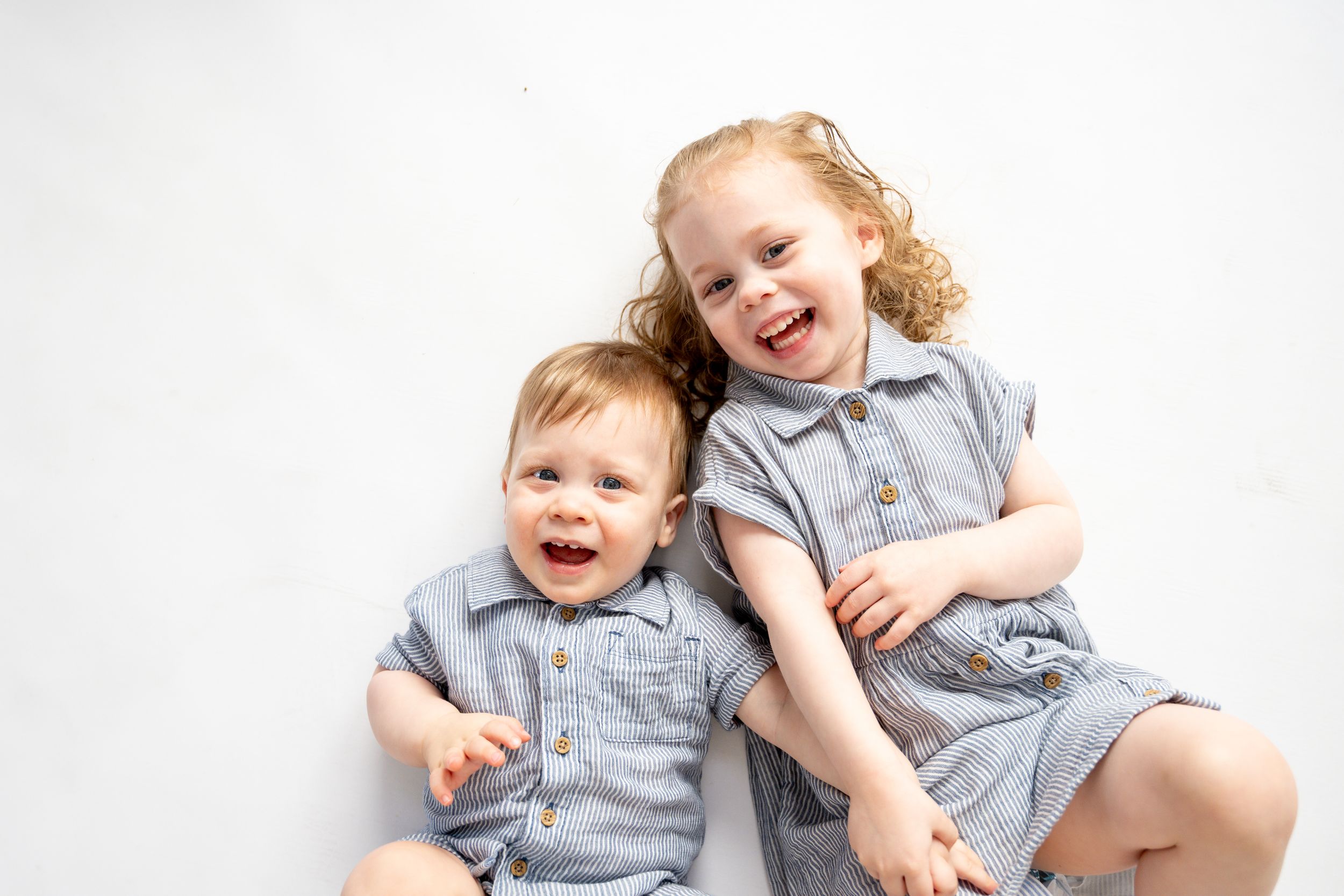 Children wearing matching gray outfits lying on a white background in various playful poses.
