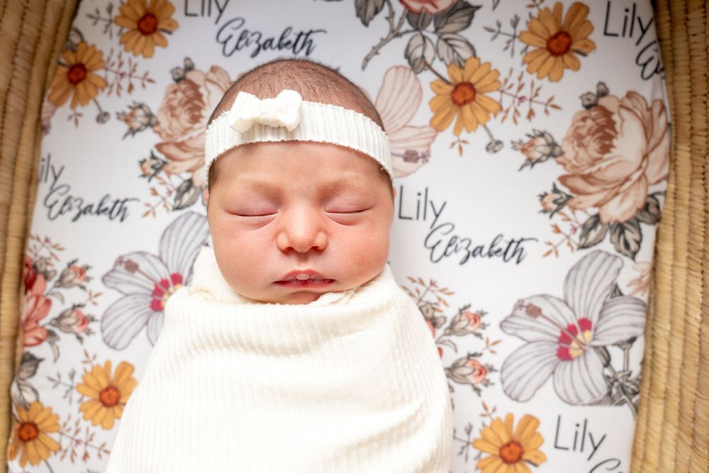A series of newborn baby photos with floral background decorations and soft white wrappings.