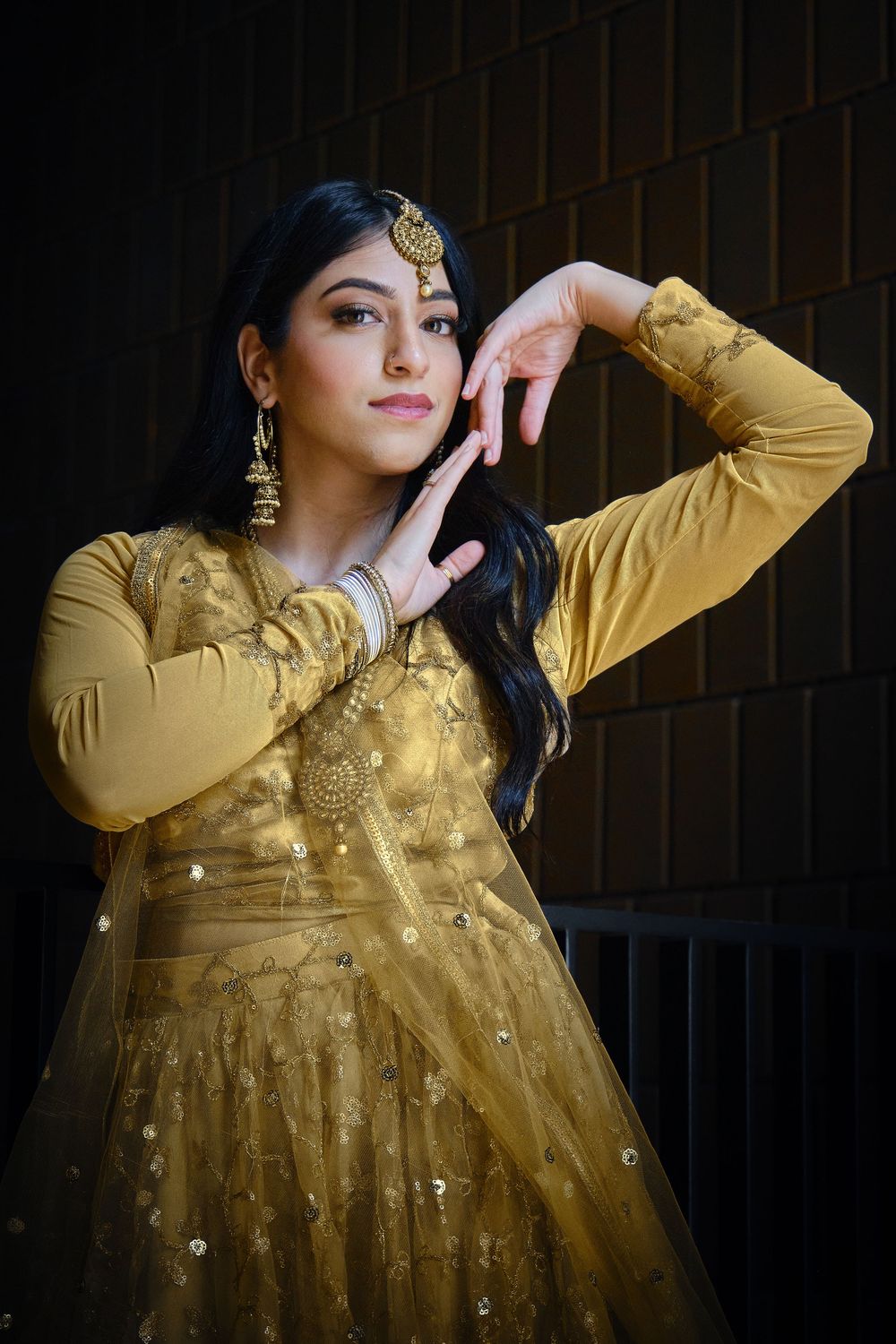 A series of fashion poses in a gold sequined dress against a dark brick wall background.