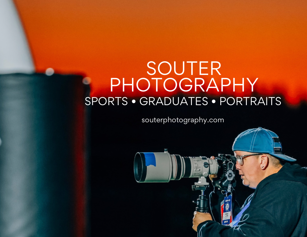 Professional photographer with telephoto lens and blue cap photographing sports events against orange background.