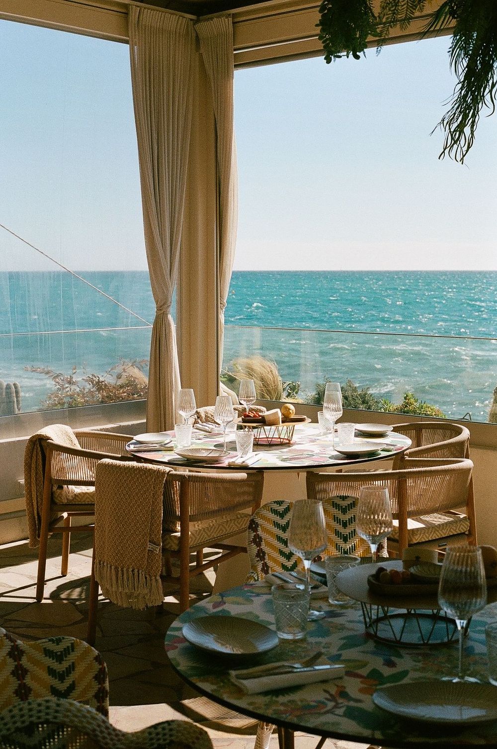 Elegant oceanside in antibes dining setup with white tablecloth and natural decor overlooking turquoise waters.