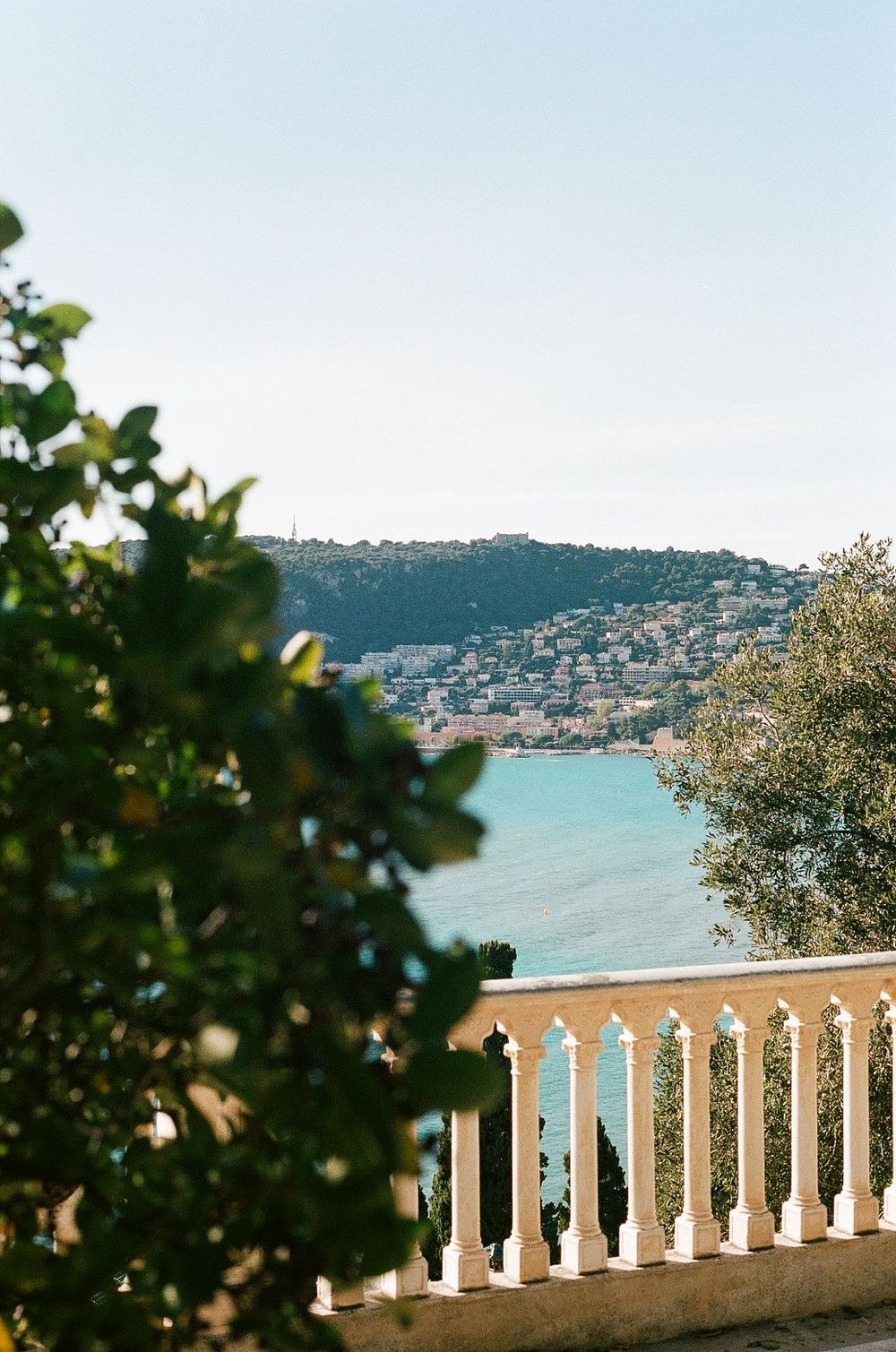 Mediterranean coastal view in antibes with white balustrade overlooking turquoise waters and hillside homes.