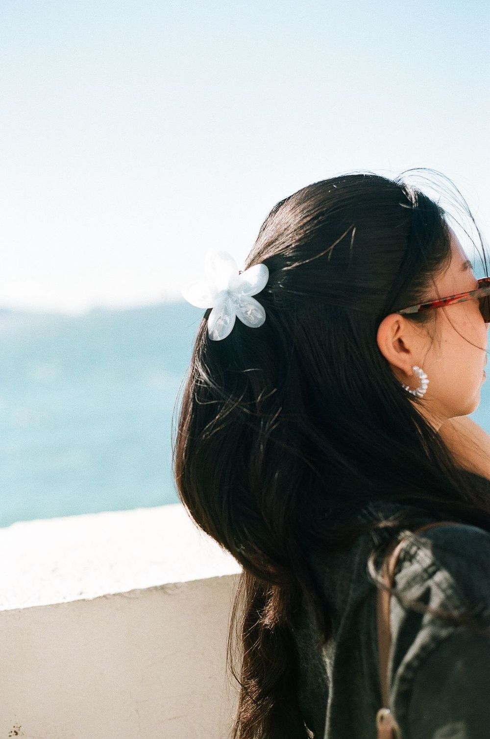 Close-up shot of a white flower hair accessory against an oceanic background in Marseille taken on film