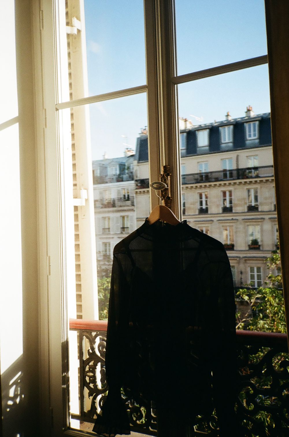 Black jacket hanging by window with Parisian building views in background.