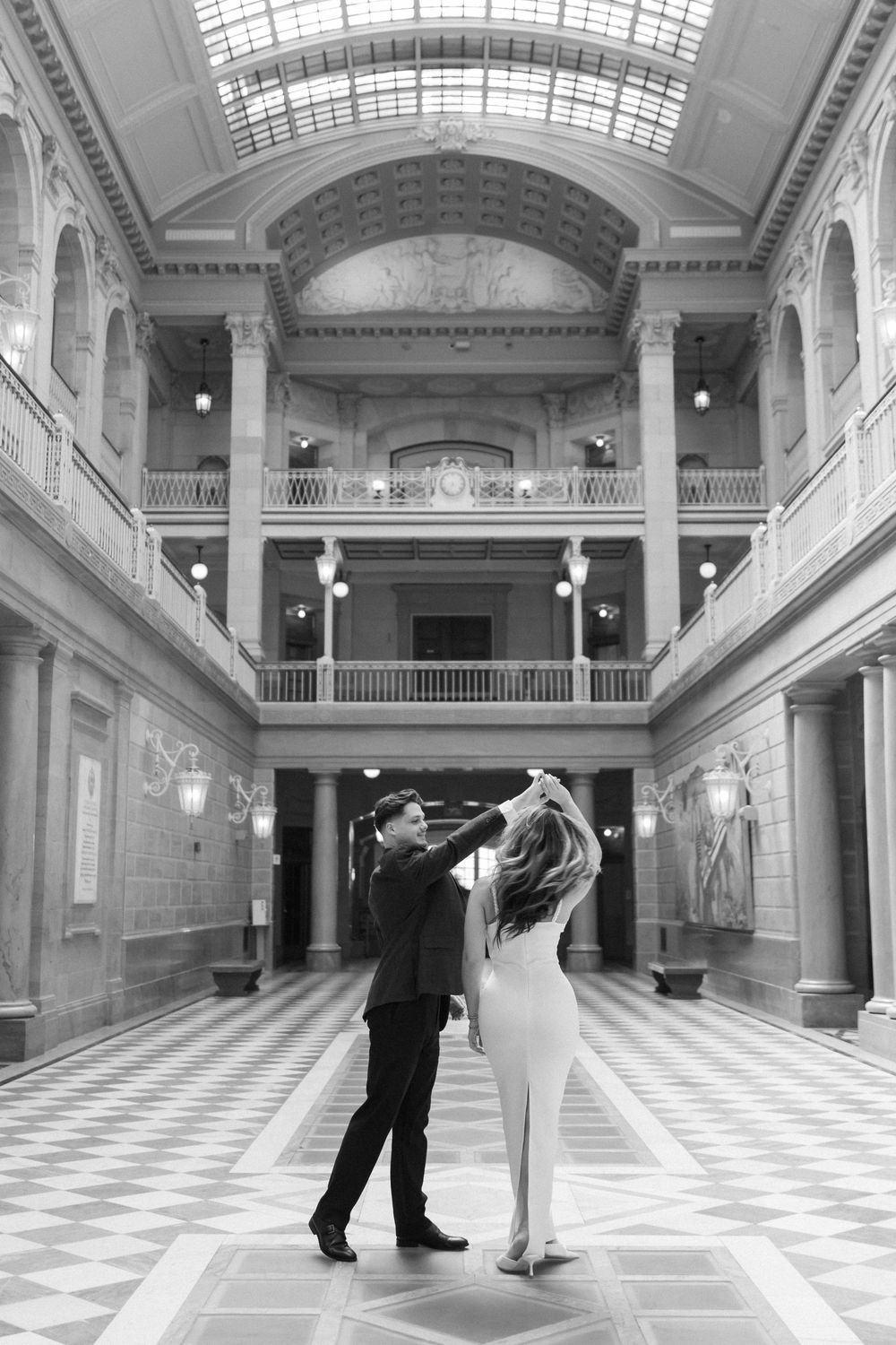 A romantic dance in a stunning marble hall with dramatic lighting and architectural details.