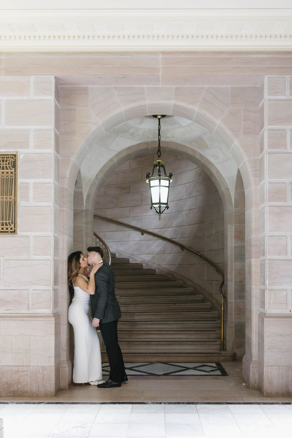 A romantic moment captured under a stone archway with classical architectural details.