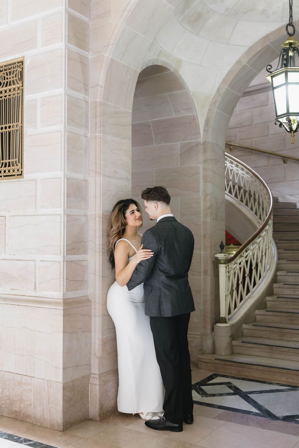 An intimate moment shared beneath an ornate stone archway with pendant lighting.
