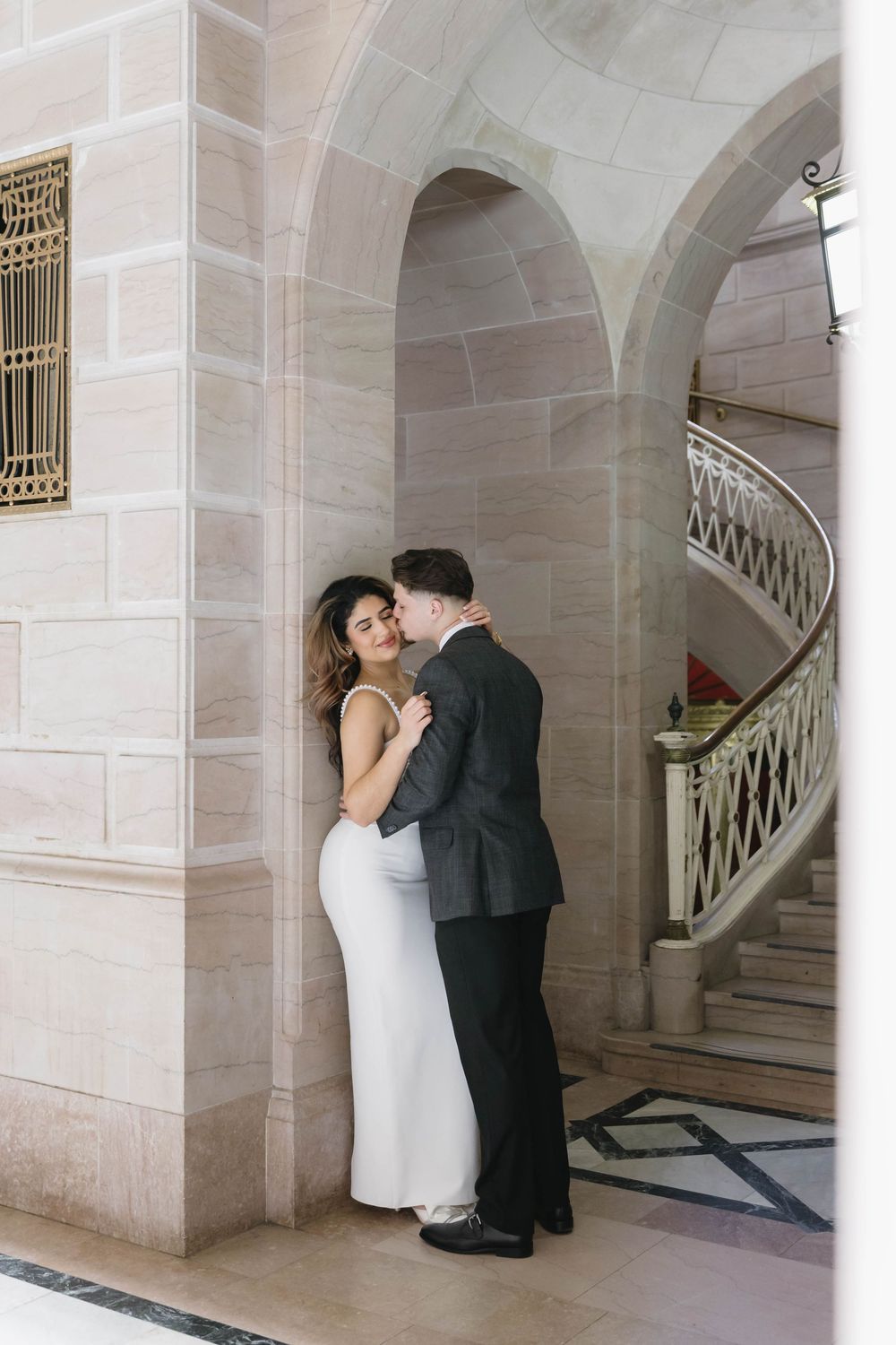Wedding couple shares tender moments against the backdrop of a classic marble staircase.
