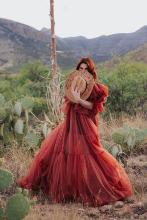 Romantic burgundy gown with dramatic ruffles photographed among desert flora and mountains.