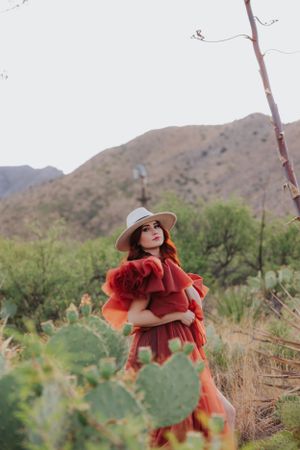 A desert fashion photoshoot featuring flowing red ruffled dress against mountainous backdrop.