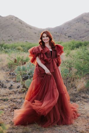A luxurious burgundy gown with ruffled details photographed in a desert setting.
