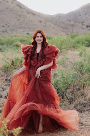 A dramatic red tulle dress billows gracefully in a desert mountain landscape.