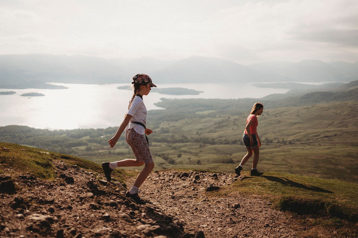 Three people enjoying the view from a hilltop overlooking a scenic landscape.