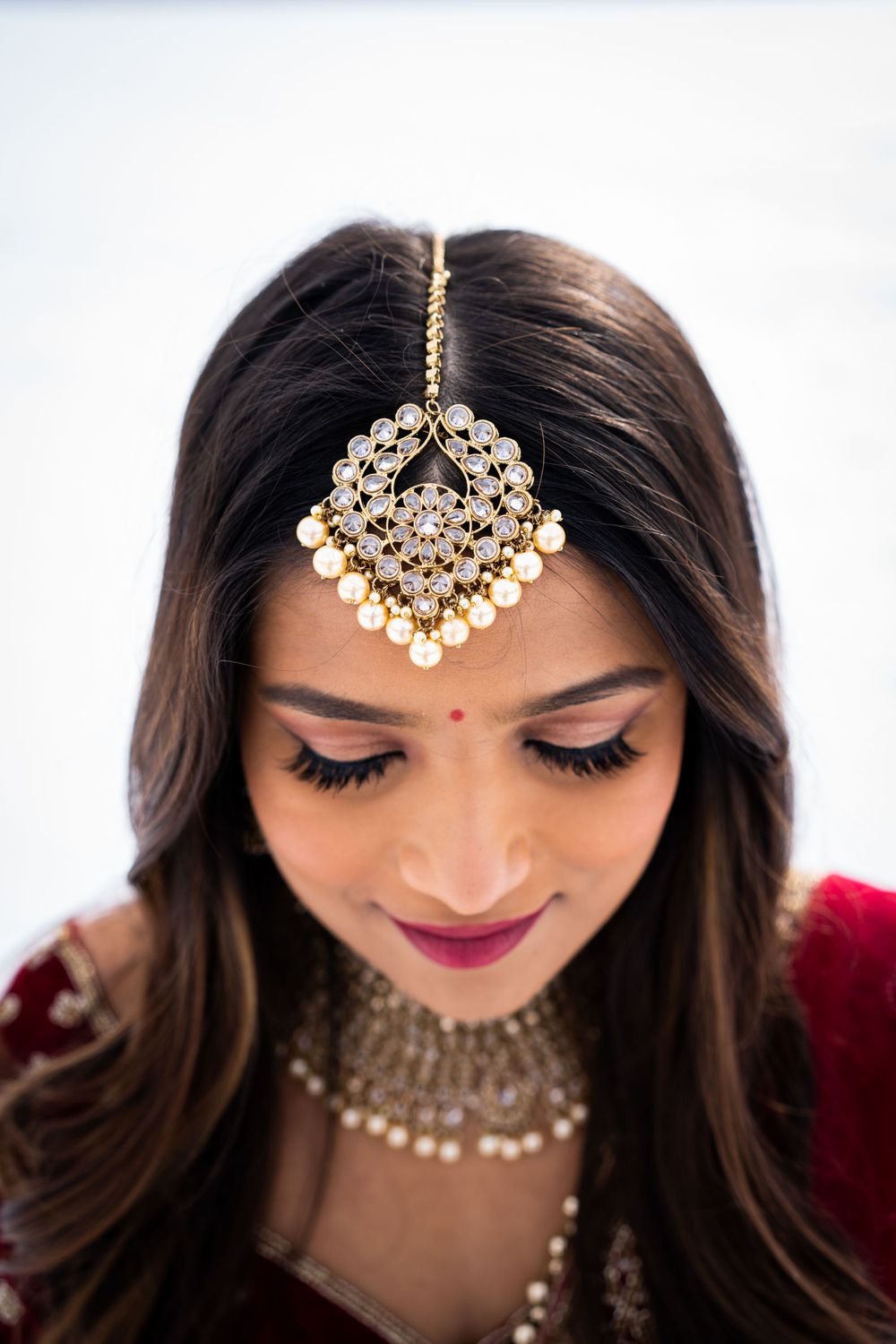 Elegant Indian bridal jewelry with pearl tikka headpiece and traditional makeup.