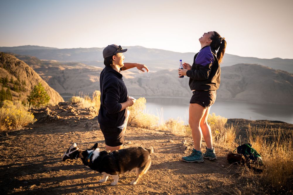 Proposal moment captured on mountain cliff during golden hour.