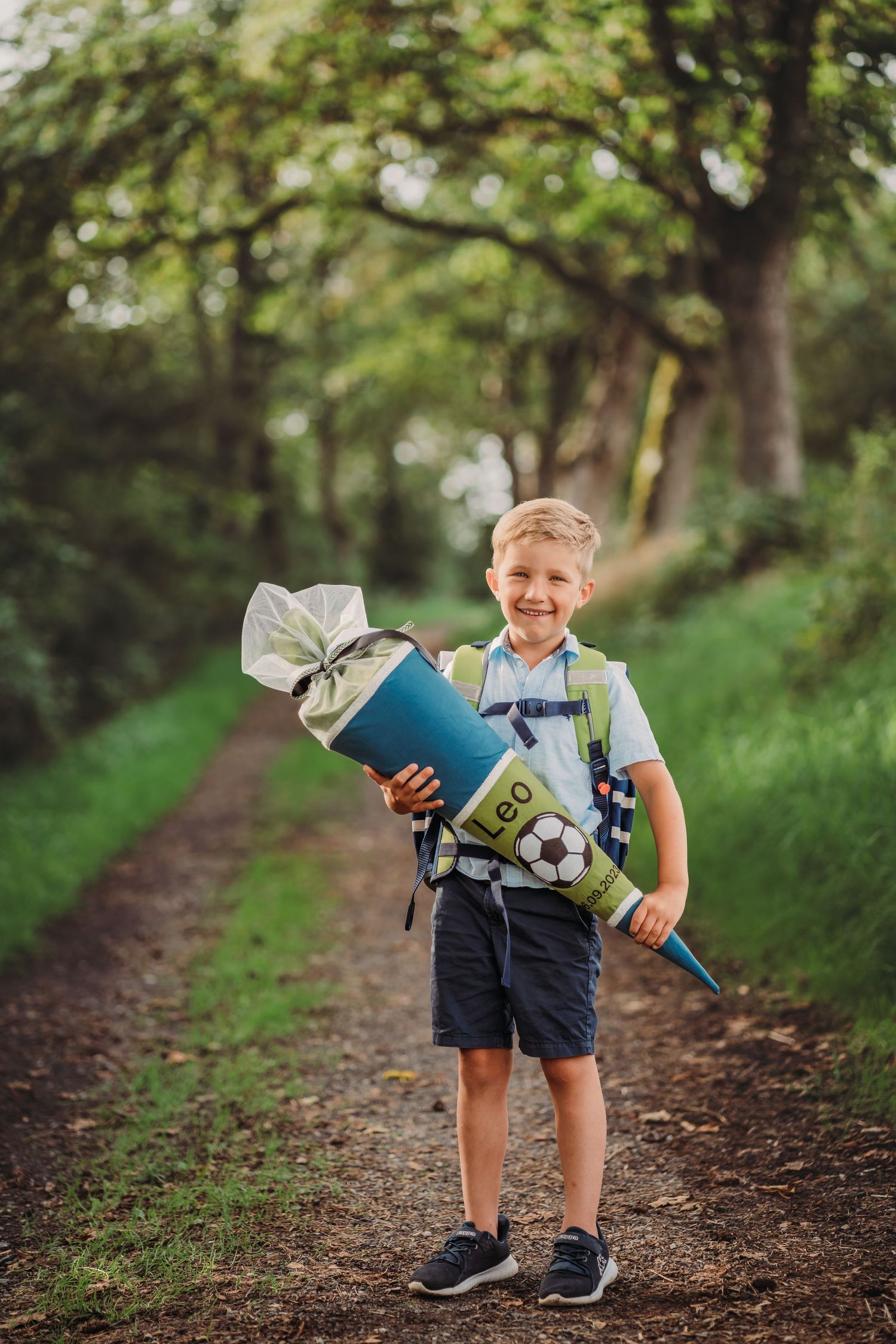 Student holding traditional German school cone on forest path.