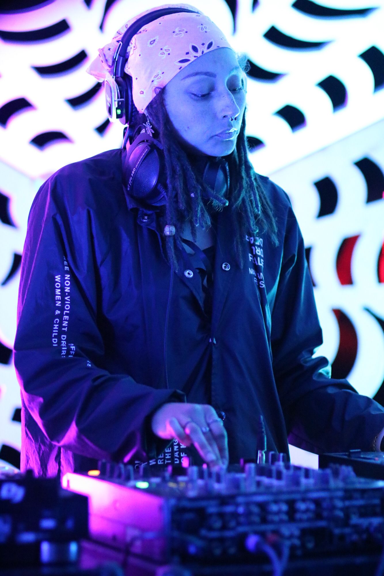DJ performing at a nightclub with blue and purple lighting effects on the equipment.