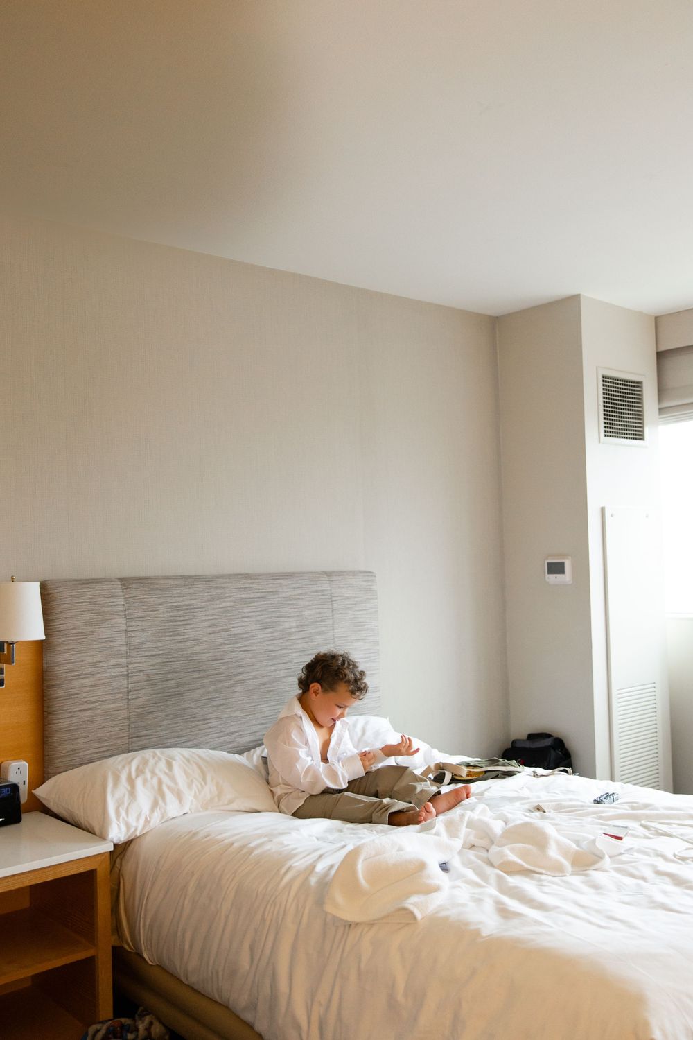 A sequence of photos showing an unmade hotel bed in a minimalist white room with morning light streaming in.