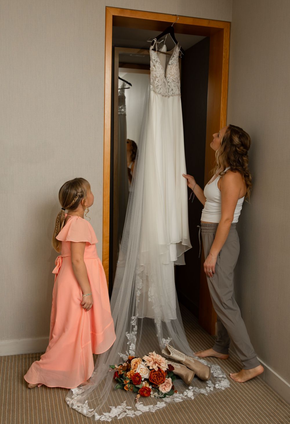 A series of wedding preparation photos showing a white wedding dress hanging and figures in coral dresses in a room.