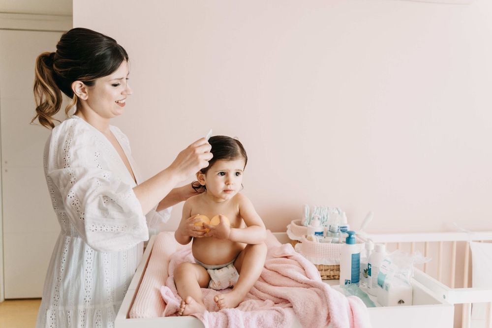 A tender bath time moment as gentle hands care for a small baby wrapped in a soft pink towel.