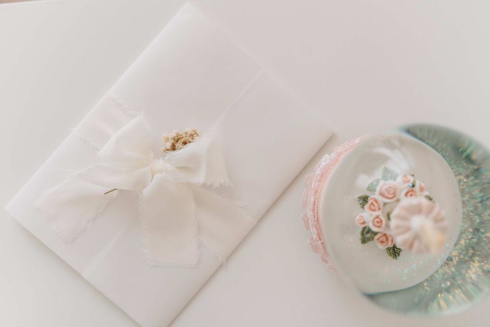 Elegant white gift wrap and floral decorated plate on light surface.
