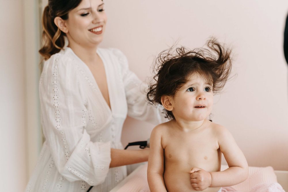 An intimate getting-ready moment captured against a light pink wall.