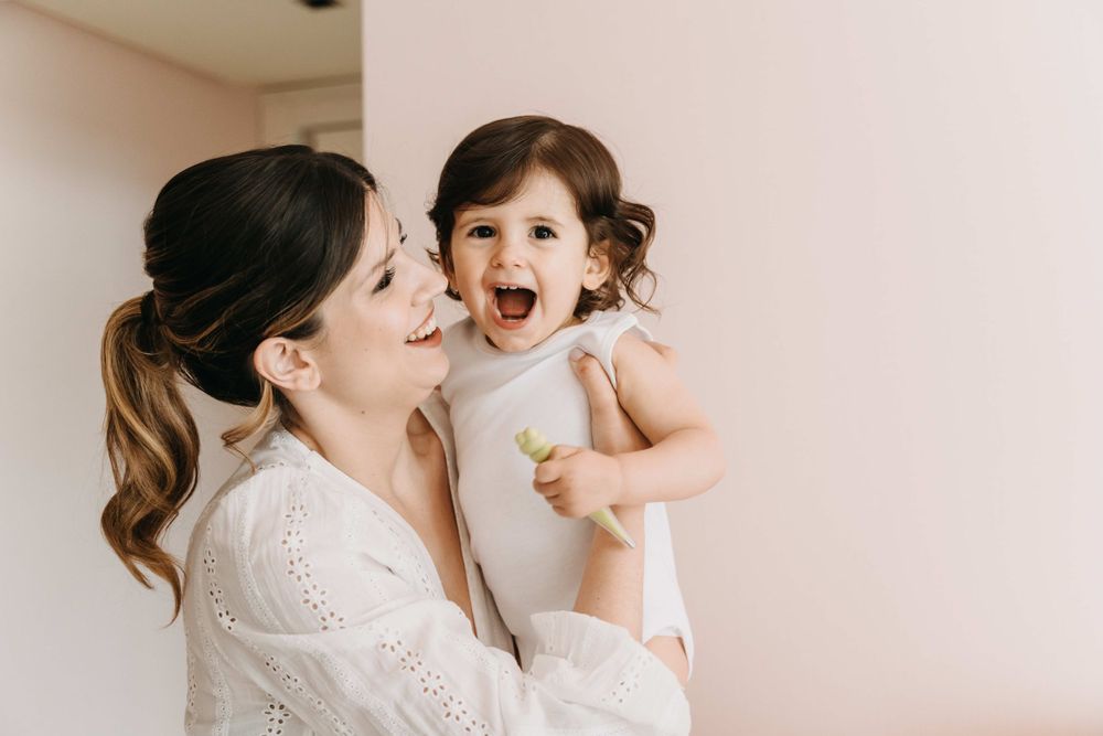 A tender moment of shared joy and laughter against a minimalist background.