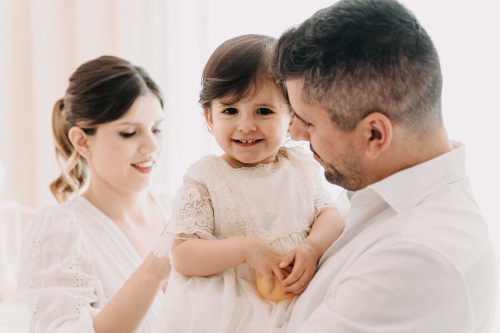 A touching family moment filled with laughter and joy against a soft pink background.