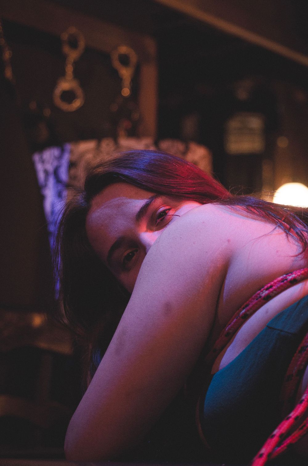 Moody portrait with dramatic red and blue lighting creating an artistic atmospheric effect.