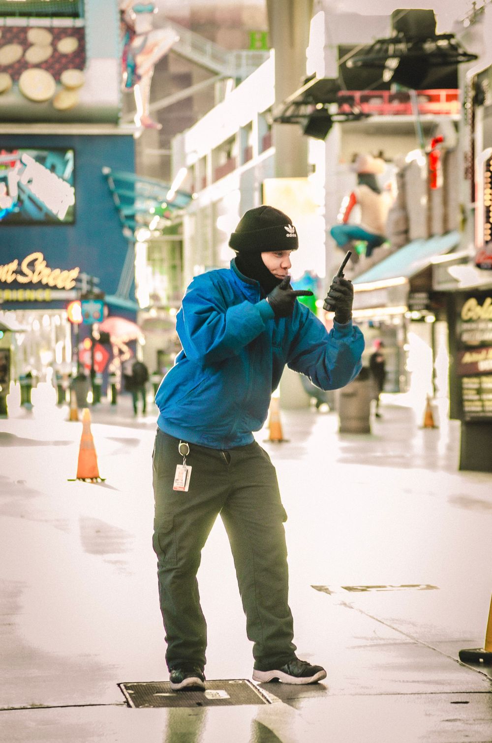 Person in blue jacket and gray pants performing dance moves in an empty shopping mall.