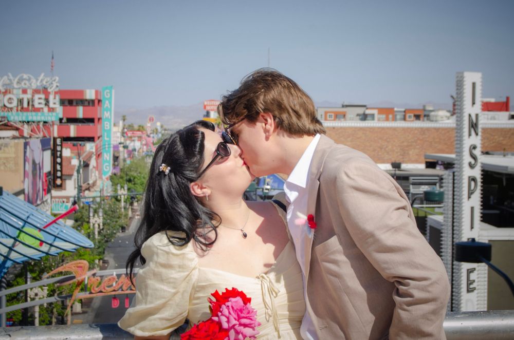 A couple sharing a romantic kiss at an outdoor amusement park.