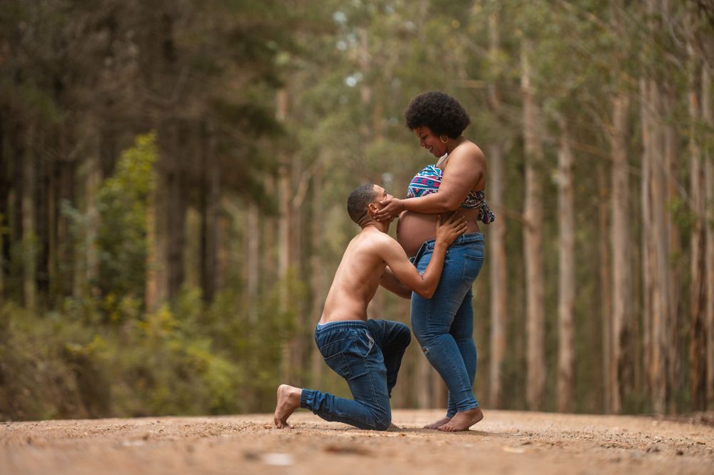 a man kneeling while kissing the stomach of a pregnant woman