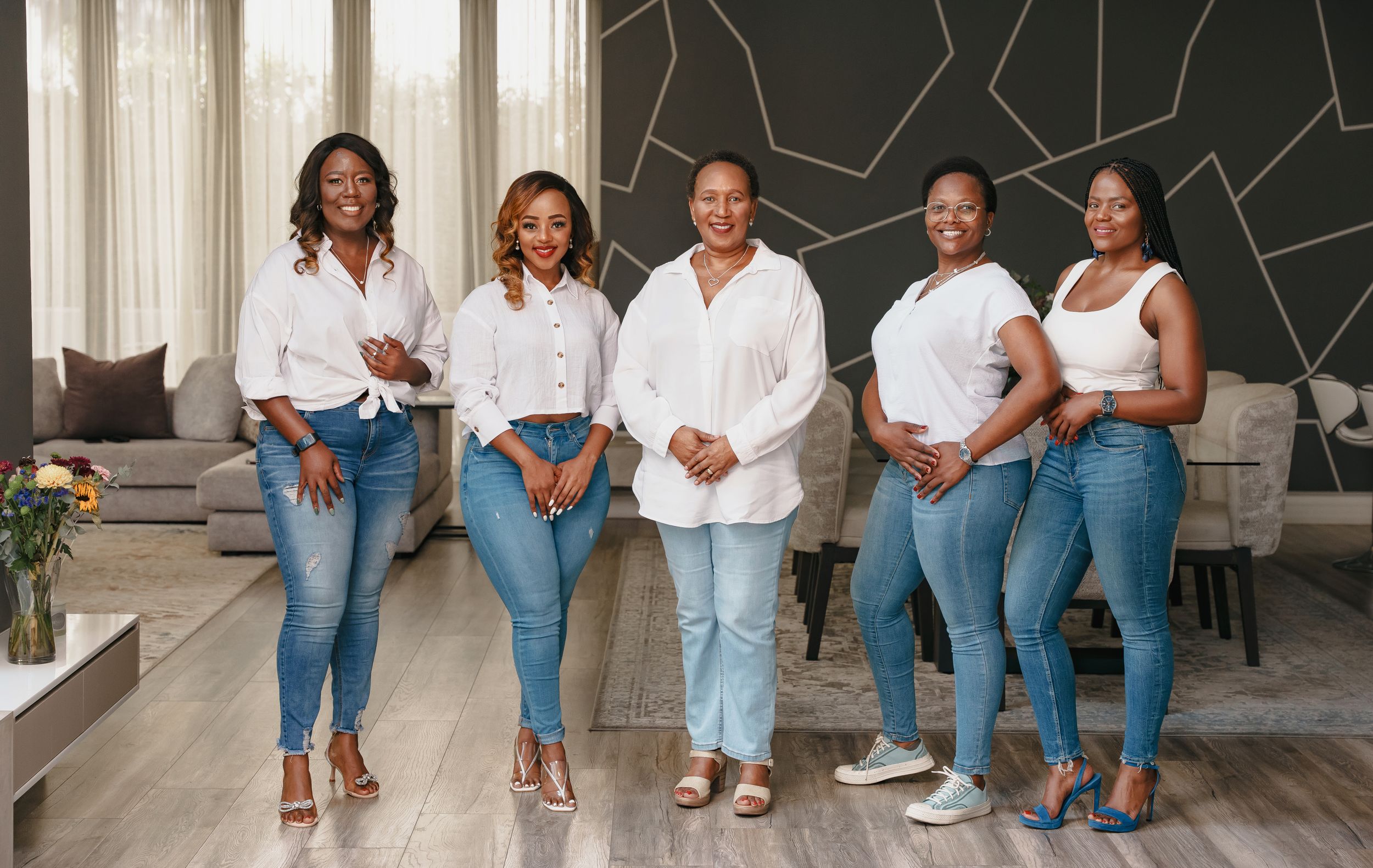 Group poses together wearing coordinated white tops and blue jeans.