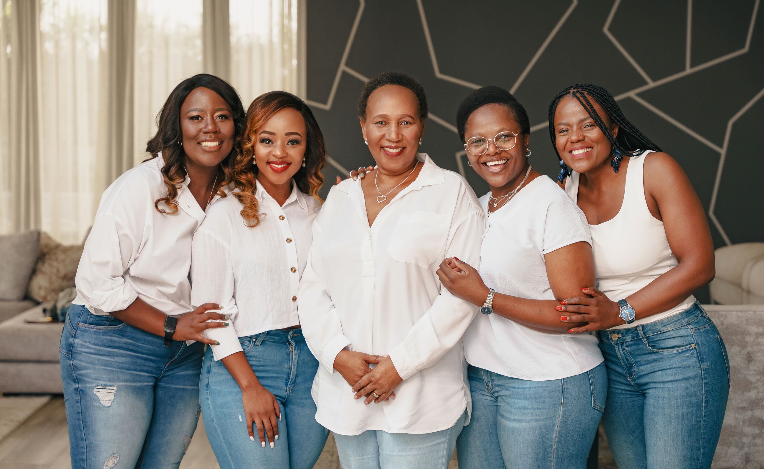Group smiles together wearing matching white tops and blue jeans.