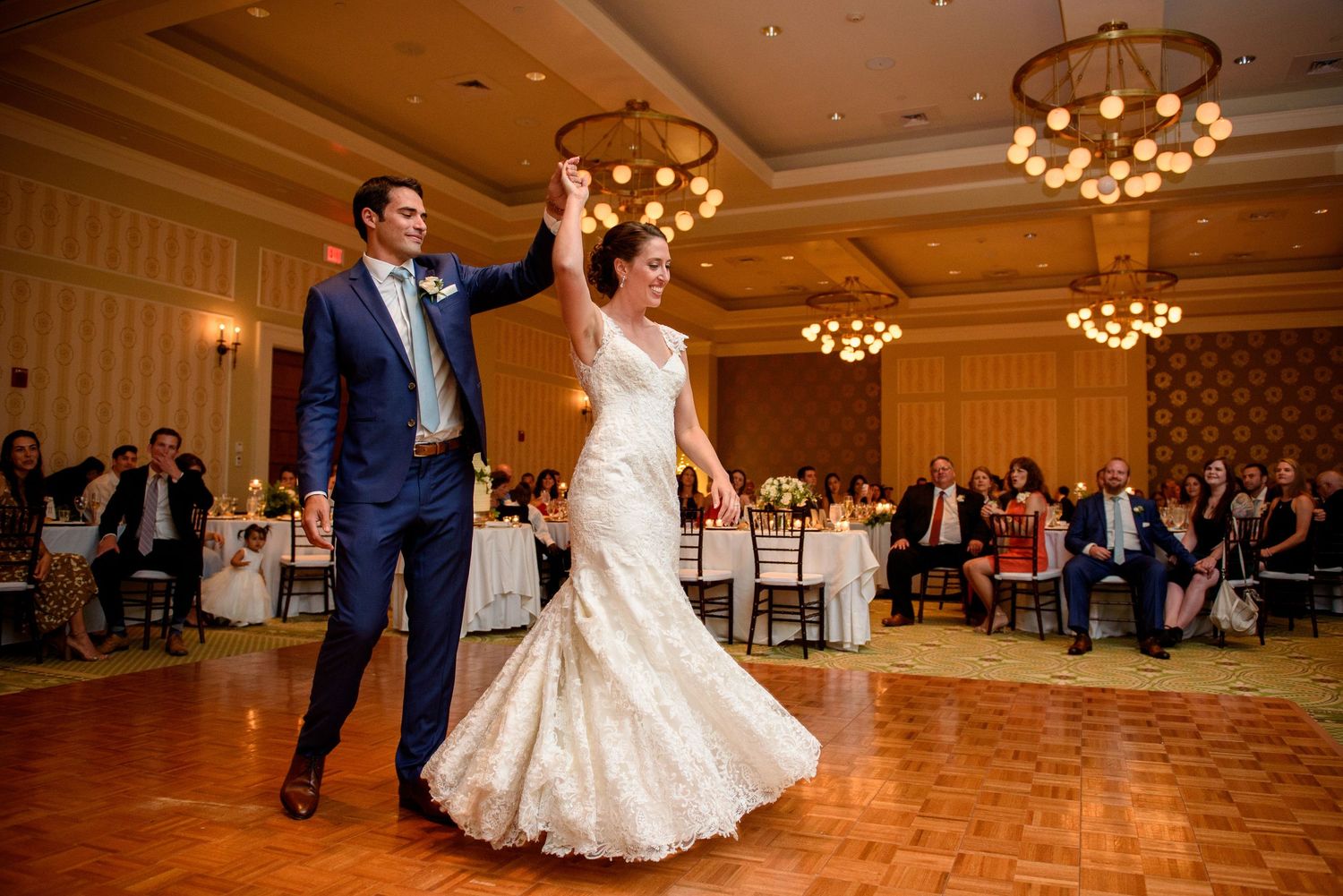 A bride and groom's first dance on a golden-lit hardwood floor at the Presidential Ballroom of the Omni Mt. Washington Hotel & Resort