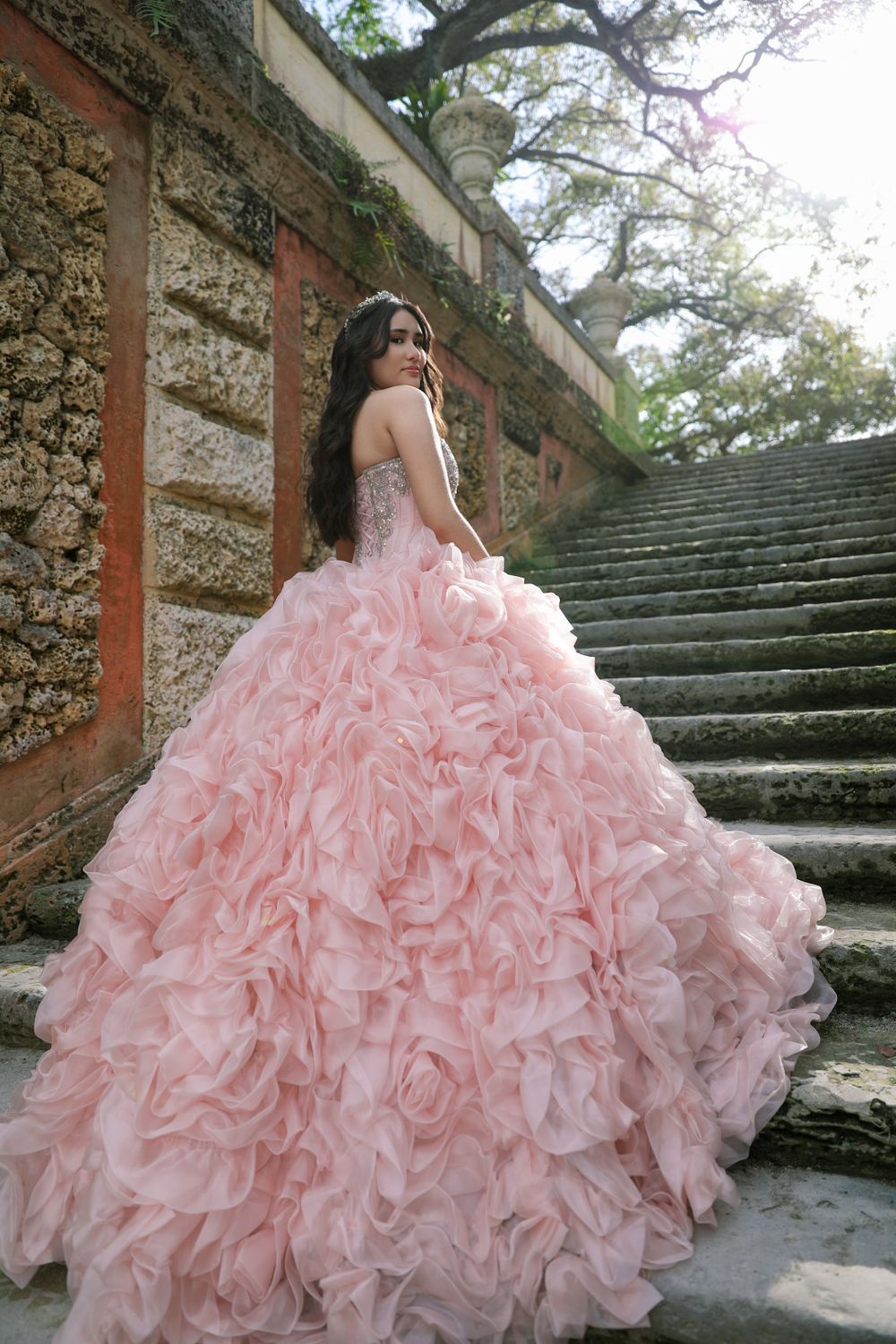 Pink ruffled quinceañera dress captured on historic stone staircase.