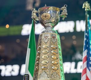 Ornate silver and gold championship trophy displayed with flags at rodeo event.
