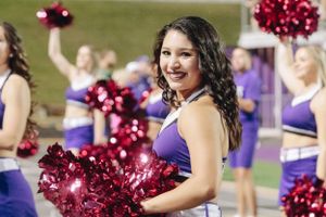 Cheerleaders in blue and red uniforms perform with pom poms at a sporting event.