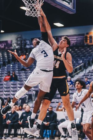 Basketball players jump for a rebound during an intense indoor game.
