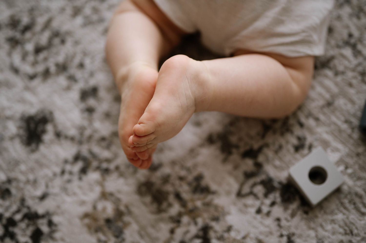 Baby feet and hands play with flour scattered on a dark surface creating messy patterns and textures.