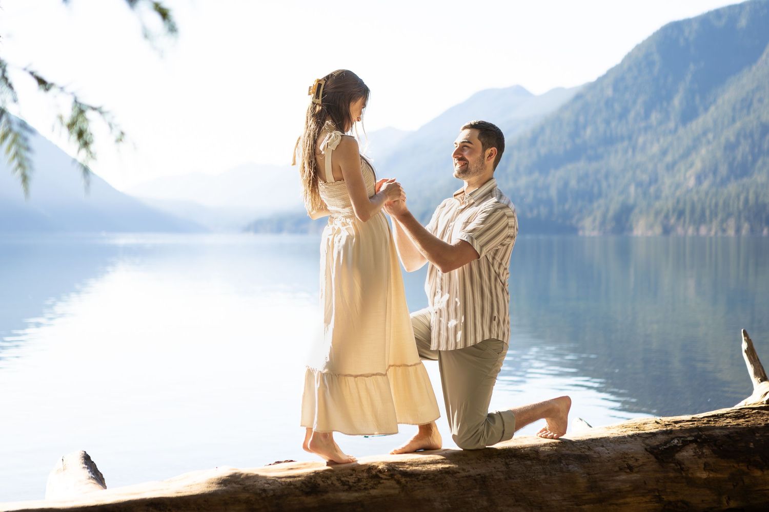 Romantic couple sitting together on a log by a serene mountain lake.