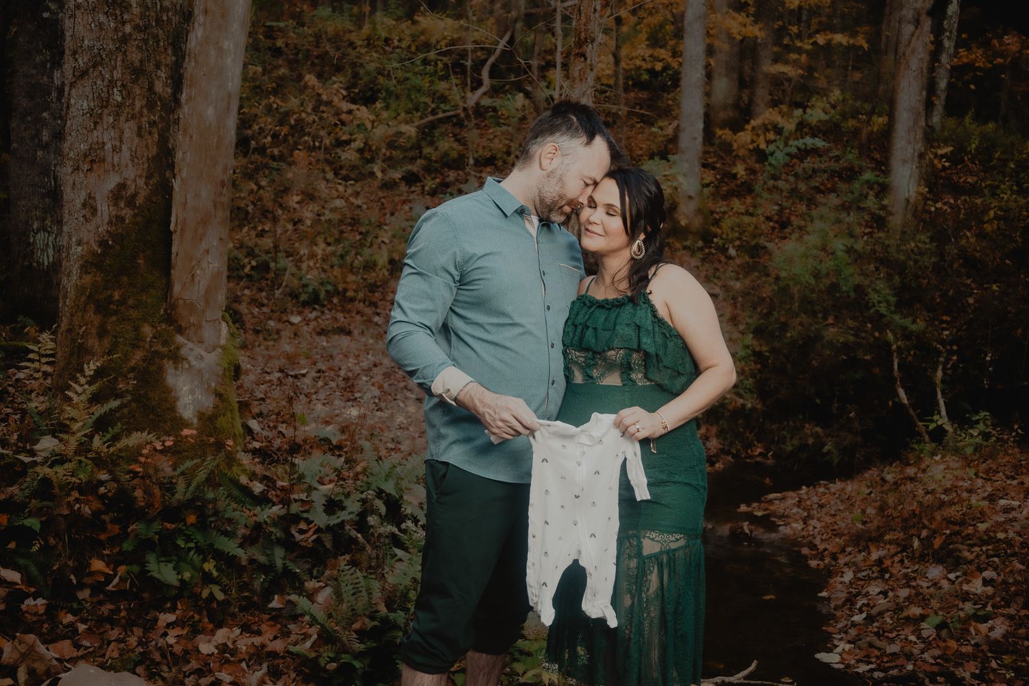 Family in green and white outfits embracing in autumn forest.