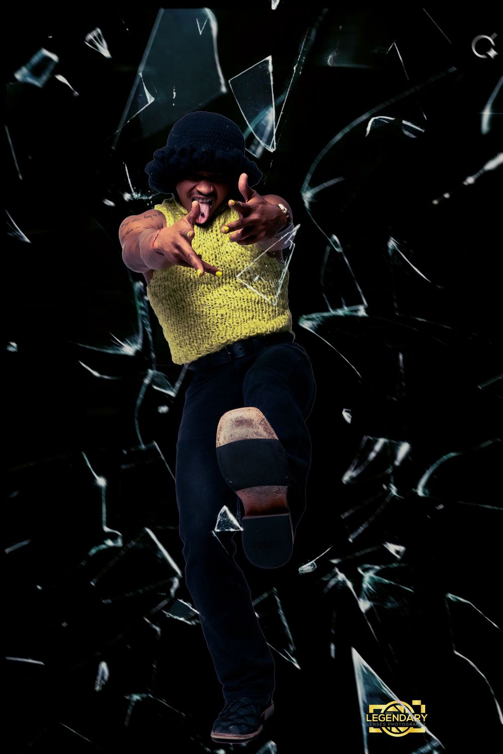 Dramatic photo of a figure bursting through shattering glass wearing a yellow top and dark pants against a black background.