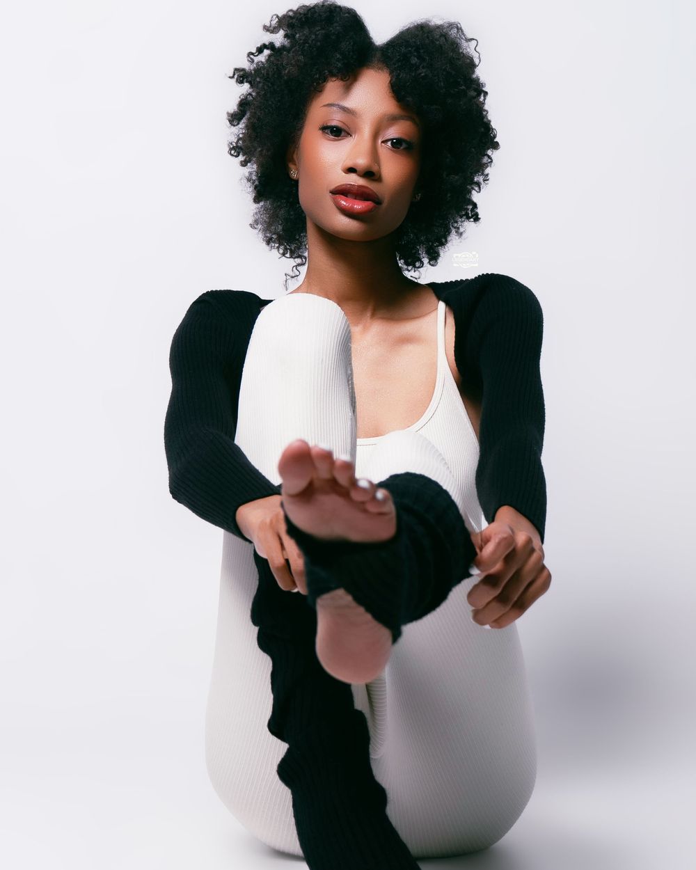 Portrait series showing a model in a white top and black cardigan striking dynamic poses against a light background.