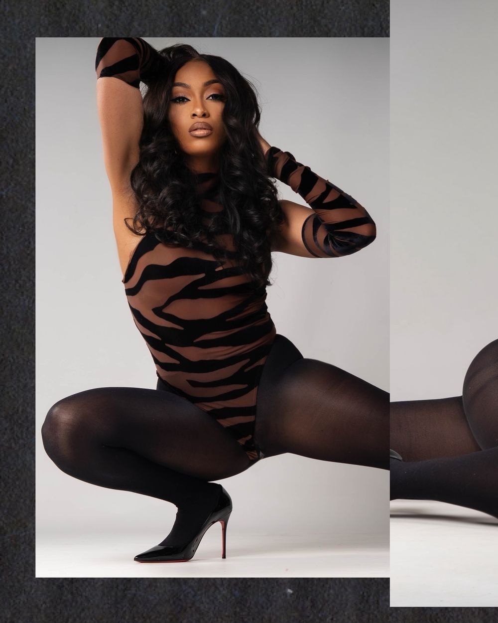 Fashion model in black and brown striped bodysuit and tights poses dynamically against white studio background.