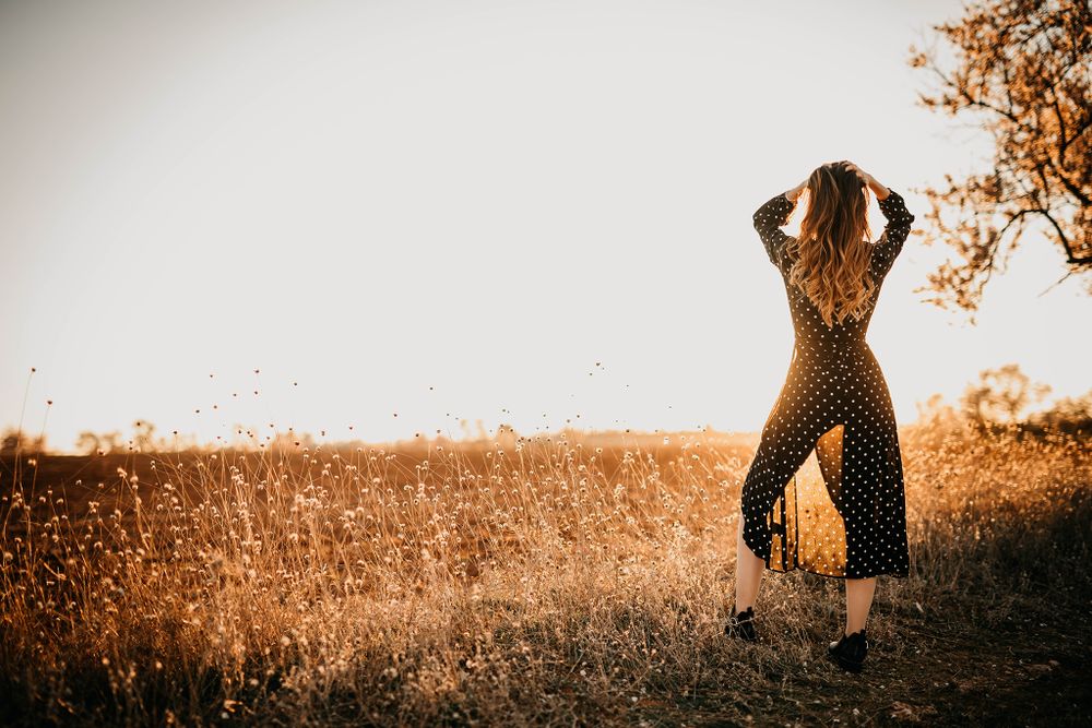 Retrato de una chica al atardecer con un vestido negro en su sesión de fotos book profesional.