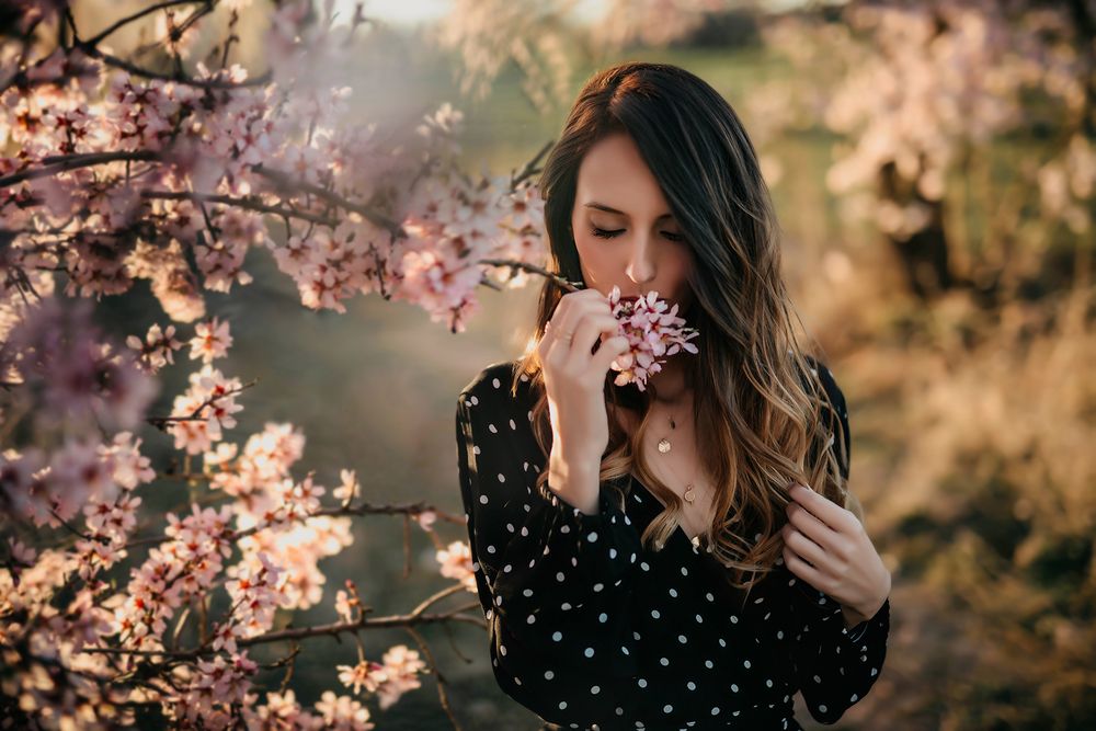 Retrato de una chica oliendo la flor de almendro en una sesión de fotos en exterior.